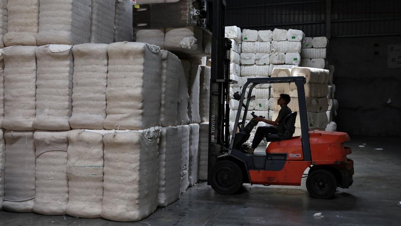 Seorang pekerja menumpuk bundel kapas mentah di gudang pabrik pembuatan benang kapas Fiotex Cotspin di Rajkot, Gujarat, India, 14 April 2026.