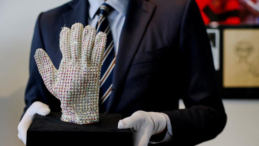 Arthur Perault, kepala Departemen Budaya Pop dan Memorabilia Aguttes, memegang sarung tangan kristal Swarovski buatan khusus yang dikenakan Michael Jackson di atas panggung selama Tur Dunia