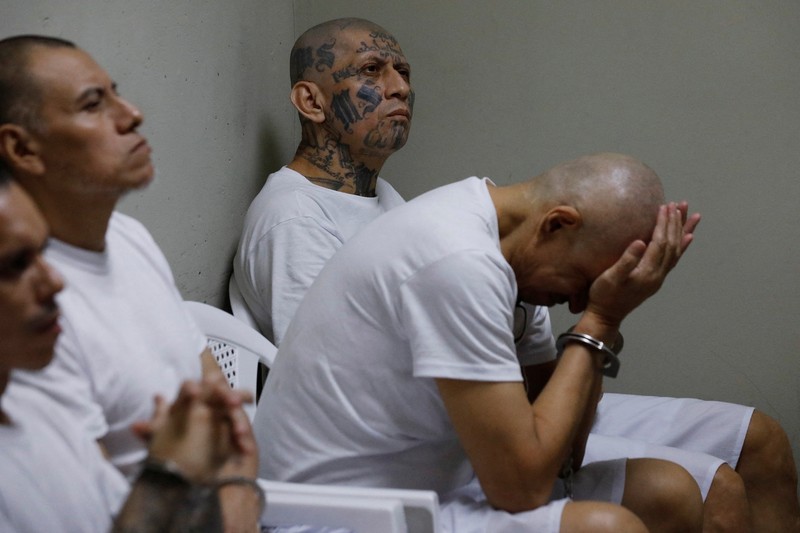 Para terduga anggota geng Mara Salvatrucha, juga dikenal sebagai MS-13, menghadiri sidang terbuka dalam persidangan massal, setelah 486 terduga anggota geng didakwa dengan lebih dari 47.000 kejahatan yang dilakukan antara tahun 2012 dan 2022, menurut jaksa, di Pusat Penahanan Terorisme (CECOT) di Tecoluca, El Salvador, 23 April 2026. (REUTERS/Jose Cabezas)