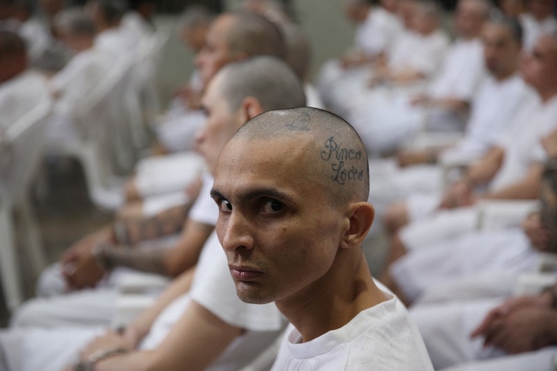 Para terduga anggota geng Mara Salvatrucha, juga dikenal sebagai MS-13, menghadiri sidang terbuka dalam persidangan massal, setelah 486 terduga anggota geng didakwa dengan lebih dari 47.000 kejahatan yang dilakukan antara tahun 2012 dan 2022, menurut jaksa, di Pusat Penahanan Terorisme (CECOT) di Tecoluca, El Salvador, 23 April 2026. (REUTERS/Jose Cabezas)