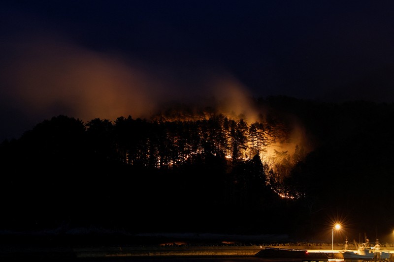 Jepang mengerahkan sekitar 1.400 petugas pemadam kebakaran dan 100 personel Pasukan Bela Diri (SDF) untuk menangani kebakaran hutan besar yang terus melanda wilayah pegunungan utara negara itu selama lima hari berturut-turut, Minggu (26/4/2026). (REUTERS/Kim Kyung-Hoon)