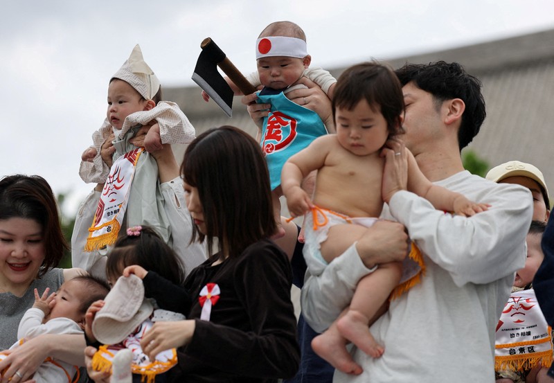 Pegulat sumo amatir menggendong bayi selama 'Nakizumo' atau kontes sumo bayi menangis di kuil Sensoji di Tokyo, Jepang, Sabtu (25/4/2026). (REUTERS/Issei Kato)