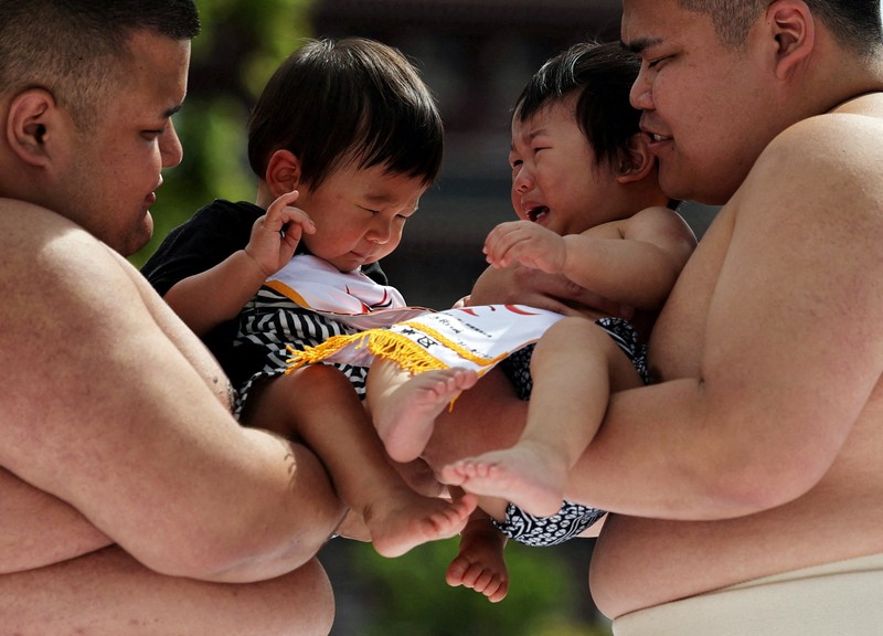 Pegulat sumo amatir menggendong bayi selama 'Nakizumo' atau kontes sumo bayi menangis di kuil Sensoji di Tokyo, Jepang, Sabtu (25/4/2026). (REUTERS/Issei Kato)