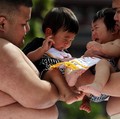 Pegulat sumo amatir menggendong bayi selama 'Nakizumo' atau kontes sumo bayi menangis di kuil Sensoji di Tokyo, Jepang, Sabtu (25/4/2026). (REUTERS/Issei Kato)