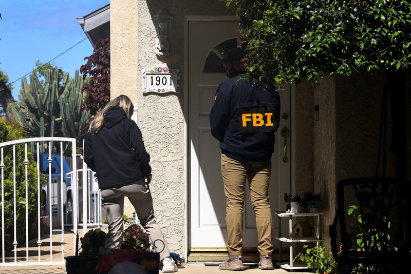An FBI member stands outside a building next to the house associated with Cole Tomas Allen, the suspect in the shooting incident in Washington at the annual White House Correspondents' Association dinner, in Torrance, California, U.S., April 26, 2026.  REUTERS/David Swanson