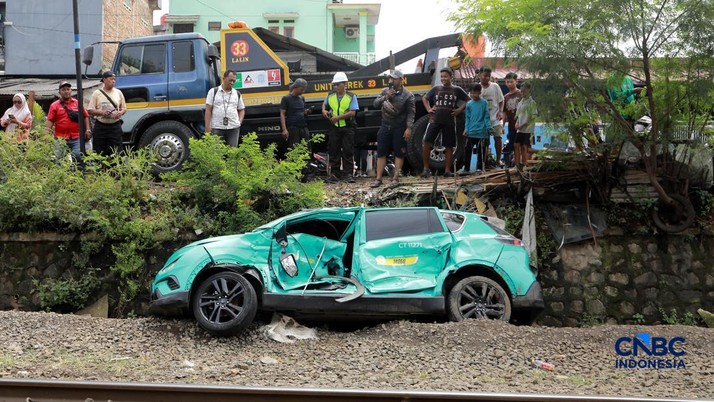 Kereta Krl melintas disamping taksi Green SM yang tertabrak KRL di perlintasan kereta Jalan Ampera, Bekasi, Selasa (28/4/2026). (CNBC Indonesia/Muhammad Sabki)