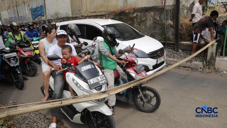 Warga melintasi perlintasan kereta Jalan Ampera, Bekasi, Selasa (28/4/2026). (CNBC Indonesia/Muhammad Sabki)
