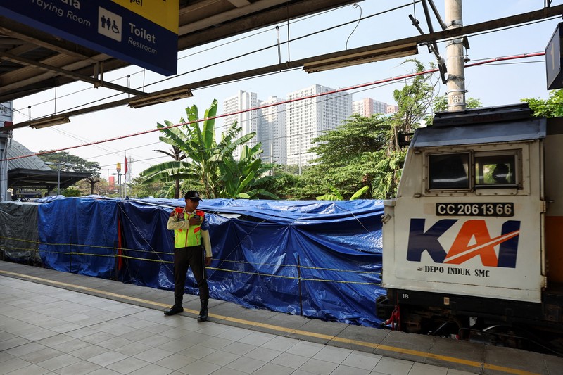 Puing-puing gerbong kereta komuter yang tertutup kain tergeletak di tanah di lokasi kejadian setelah tabrakan fatal antara kereta komuter dan kereta jarak jauh pada hari Senin, di Bekasi, pinggiran Jakarta, Indonesia, 29 April 2026. (REUTERS/Willy Kurniawan)