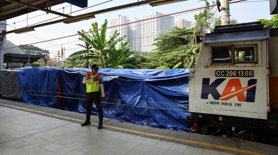 Seorang petugas keamanan berdiri di dekat puing-puing gerbong kereta komuter yang tertutup, tergeletak di lokasi setelah tabrakan fatal antara kereta komuter dan kereta jarak jauh pada hari Senin, di Bekasi, pinggiran Jakarta, Indonesia, 29 April 202