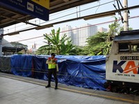 Seorang petugas keamanan berdiri di dekat puing-puing gerbong kereta komuter yang tertutup, tergeletak di lokasi setelah tabrakan fatal antara kereta komuter dan kereta jarak jauh pada hari Senin, di Bekasi, pinggiran Jakarta, Indonesia, 29 April 202
