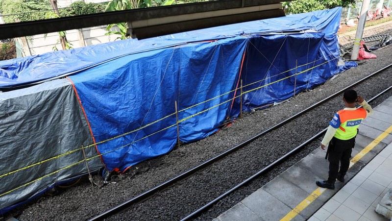 Seorang petugas keamanan berdiri di dekat puing-puing gerbong kereta komuter yang tertutup, tergeletak di lokasi setelah tabrakan fatal antara kereta komuter dan kereta jarak jauh pada hari Senin, di Bekasi, pinggiran Jakarta, Indonesia, 29 April 2026.