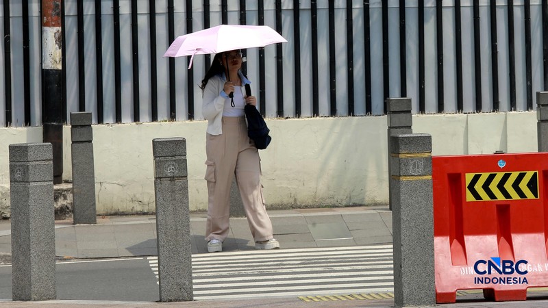 Warga berjalan dengan menutup kepala untuk berlindung dari terik matahari di Sudirman, Jakarta, Rabu (29/4/2026). (CNBC Indonesia/Muhammad Sabki)
