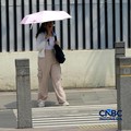 Warga berjalan dengan menutup kepala untuk berlindung dari terik matahari di Sudirman, Jakarta, Rabu (29/4/2026). (CNBC Indonesia/Muhammad Sabki)