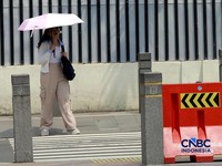 Warga berjalan dengan menutup kepala untuk berlindung dari terik matahari di Sudirman, Jakarta, Rabu (29/4/2026). (CNBC Indonesia/Muhammad Sabki)