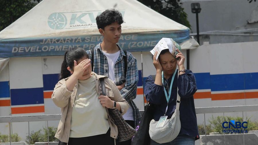 Warga berjalan dengan menutup kepala untuk berlindung dari terik matahari di Sudirman, Jakarta, Rabu (29/4/2026). (CNBC Indonesia/Muhammad Sabki)