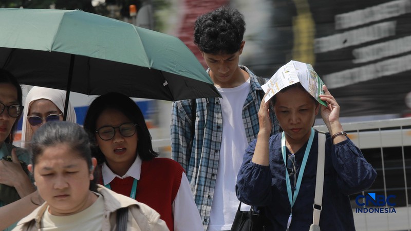 Warga berjalan dengan menutup kepala untuk berlindung dari terik matahari di Sudirman, Jakarta, Rabu (29/4/2026). (CNBC Indonesia/Muhammad Sabki)