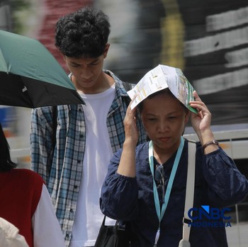 Warga berjalan dengan menutup kepala untuk berlindung dari terik matahari di Sudirman, Jakarta, Rabu (29/4/2026). (CNBC Indonesia/Muhammad Sabki)