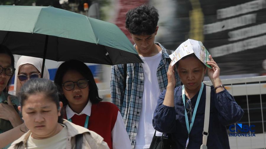 Warga berjalan dengan menutup kepala untuk berlindung dari terik matahari di Sudirman, Jakarta, Rabu (29/4/2026).