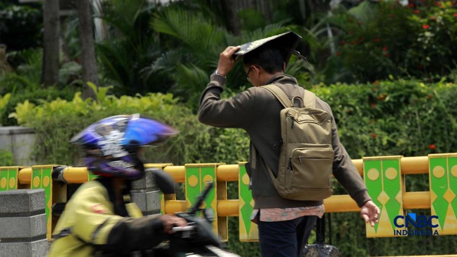 Warga berjalan dengan menutup kepala untuk berlindung dari terik matahari di Sudirman, Jakarta, Rabu (29/4/2026).