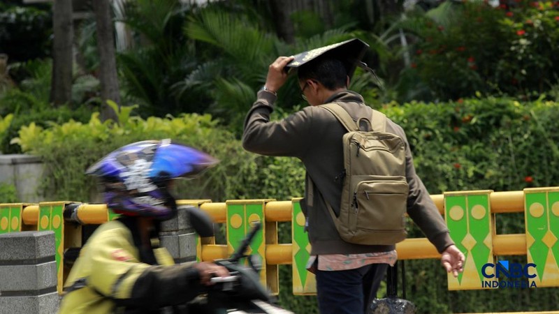 Warga berjalan dengan menutup kepala untuk berlindung dari terik matahari di Sudirman, Jakarta, Rabu (29/4/2026).