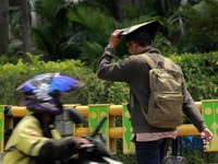 Warga berjalan dengan menutup kepala untuk berlindung dari terik matahari di Sudirman, Jakarta, Rabu (29/4/2026). (CNBC Indonesia/Muhammad Sabki)