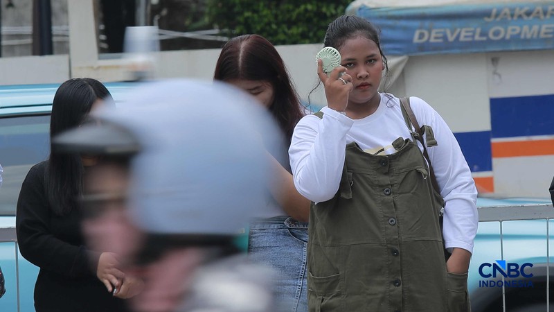 Warga berjalan dengan menutup kepala untuk berlindung dari terik matahari di Sudirman, Jakarta, Rabu (29/4/2026). (CNBC Indonesia/Muhammad Sabki)