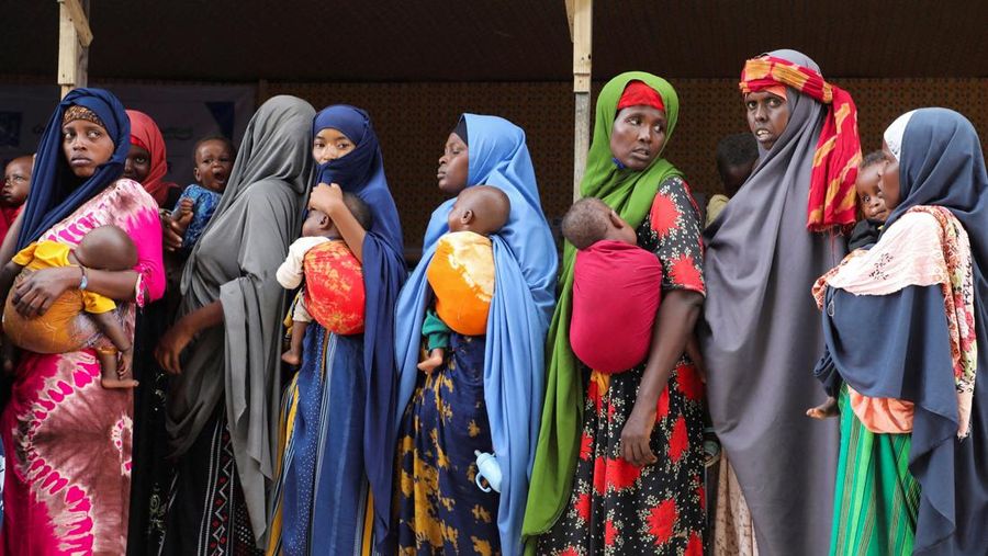 Perempuan pengungsi internal Somalia menggendong anak-anak mereka saat mengantre selama kunjungan Wakil Sekretaris Jenderal PBB untuk Urusan Kemanusiaan dan Koordinator Bantuan Darurat Tom Fletcher (tidak terlihat dalam foto), karena kekurangan makanan terapeutik yang menyelamatkan jiwa akibat gangguan pengiriman karena perang Iran telah memaksa klinik yang merawat anak-anak yang kekurangan gizi parah untuk menolak pasien dan membatasi persediaan di Somalia yang dilanda kekeringan, di sebuah kamp di pinggiran Mogadishu, Somalia, 28 April 2026.