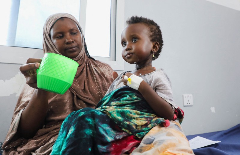 Seorang perempuan Somalia yang mengungsi di dalam negeri memberi makan anaknya yang kekurangan gizi di rumah sakit Daynile karena kekurangan makanan terapeutik yang menyelamatkan nyawa akibat gangguan pengiriman karena perang Iran telah memaksa klinik-klinik yang merawat anak-anak yang sangat kekurangan gizi untuk menolak pasien dan membatasi persediaan di Somalia yang dilanda kekeringan, di distrik Daynile, Mogadishu, Somalia, 20 April 2026. (REUTERS/Feisal Omar)