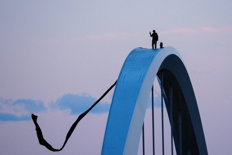 Seorang pengunjuk rasa  berada di atas Jembatan Memorial Frederick Douglass pada Hari Buruh, di Washington, D.C., AS, Jumat (1/5/2026). (REUTERS/Aaron Schwartz)