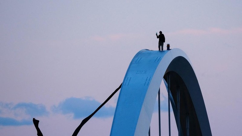 Seorang pengunjuk rasa  berada di atas Jembatan Memorial Frederick Douglass pada Hari Buruh, di Washington, D.C., AS, Jumat (1/5/2026). (REUTERS/Aaron Schwartz)