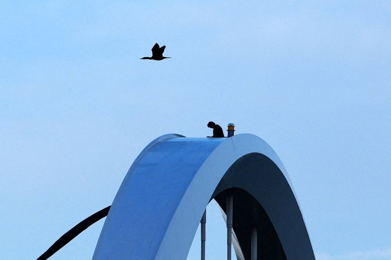 Seorang pengunjuk rasa  berada di atas Jembatan Memorial Frederick Douglass pada Hari Buruh, di Washington, D.C., AS, Jumat (1/5/2026). (REUTERS/Aaron Schwartz)