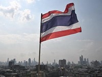 The Thai flag is seen with the city skyline the day after the general election, in Bangkok on February 9, 2026. (Photo by Lillian SUWANRUMPHA / AFP)