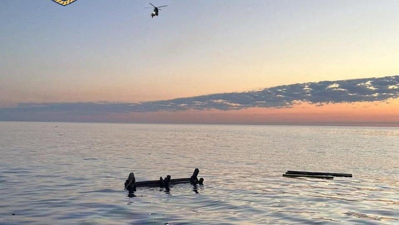 Sebuah pesawat terbang melintas selama operasi penyelamatan setelah sebuah kapal kargo kandas dan tenggelam di lepas pantai pulau Andros, Yunani, 6 Mei 2026.