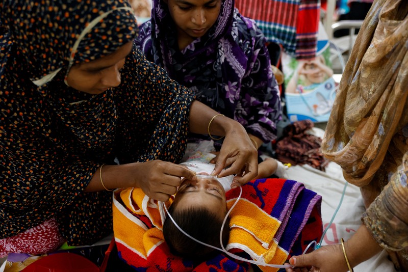 Para orang tua membantu anak-anak yang terinfeksi campak untuk menyesuaikan masker nebulizer mereka saat menerima perawatan di Rumah Sakit DNCC, menyusul wabah yang terjadi di seluruh negeri, di Dhaka, Bangladesh, 6 Mei 2026. (REUTERS/Mohammad Ponir  Hossain)