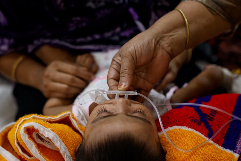 Para orang tua membantu anak-anak yang terinfeksi campak untuk menyesuaikan masker nebulizer mereka saat menerima perawatan di Rumah Sakit DNCC, menyusul wabah yang terjadi di seluruh negeri, di Dhaka, Bangladesh, 6 Mei 2026. (REUTERS/Mohammad Ponir  Hossain)