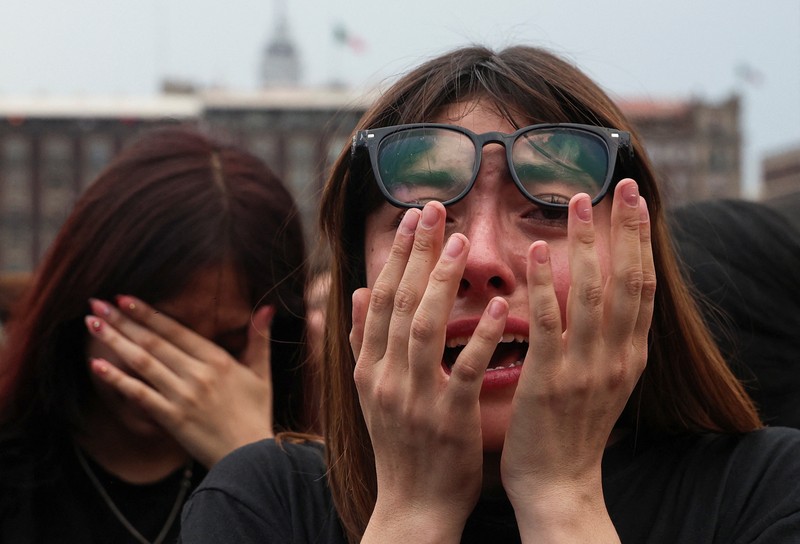 Mexico's President Claudia Sheinbaum and members of South Korean Kpop boy band BTS react as they stand on a balcony of the National Palace ahead of a series of concerts on the BTS World Tour