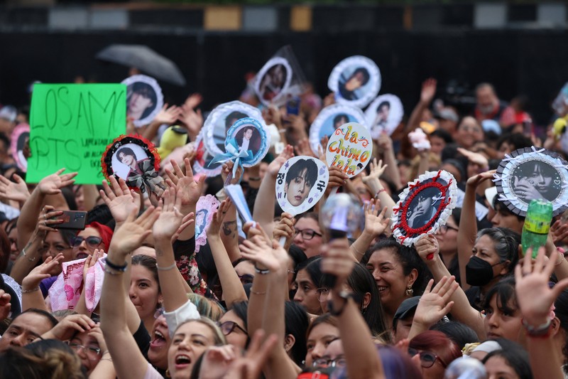 Mexico's President Claudia Sheinbaum and members of South Korean Kpop boy band BTS react as they stand on a balcony of the National Palace ahead of a series of concerts on the BTS World Tour