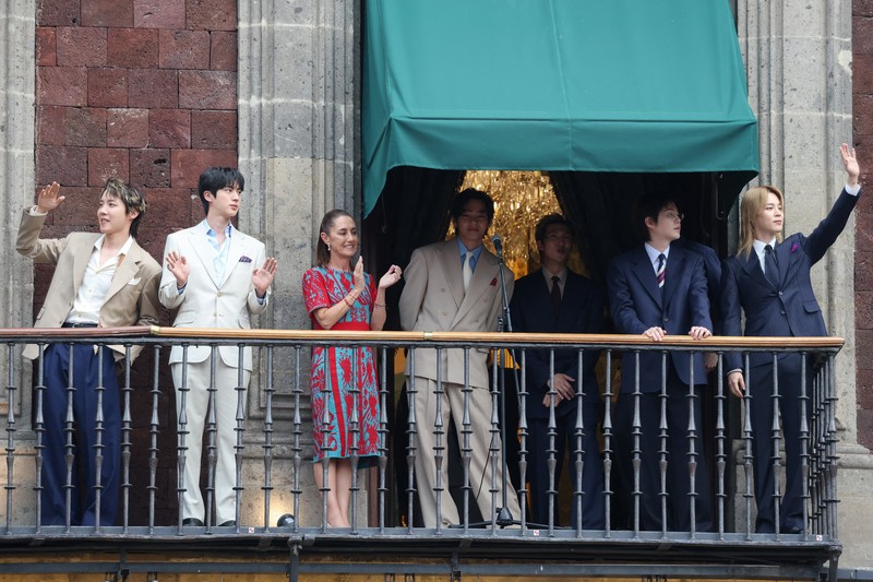 Mexico's President Claudia Sheinbaum and members of South Korean Kpop boy band BTS react as they stand on a balcony of the National Palace ahead of a series of concerts on the BTS World Tour