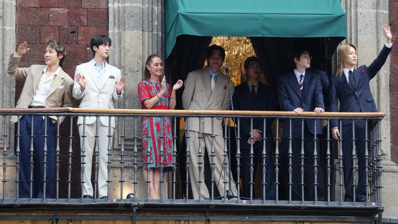 Mexico's President Claudia Sheinbaum and members of South Korean Kpop boy band BTS react as they stand on a balcony of the National Palace ahead of a series of concerts on the BTS World Tour