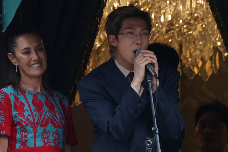 Mexico's President Claudia Sheinbaum and members of South Korean Kpop boy band BTS react as they stand on a balcony of the National Palace ahead of a series of concerts on the BTS World Tour