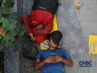 Sejumlah pekerja beristirahat di trotoar Jalan Rasuna Said, Jakarta, Kamis (7/5/2026). (CNBC Indonesia/Tri Susilo)
