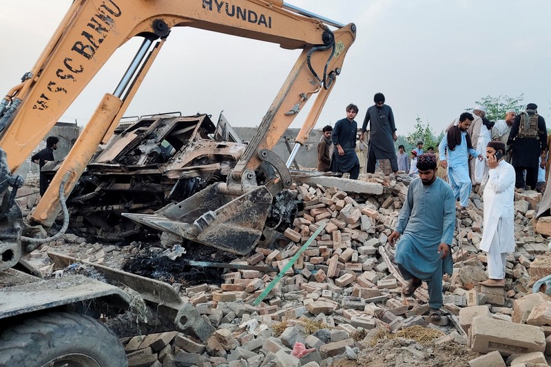 Warga berkumpul saat alat berat membersihkan puing-puing pos polisi yang rusak akibat serangan bom mobil di Bannu, provinsi Khyber Pakhtunkhwa, Pakistan, 10 Mei 2026. REUTERS/Ehsan Khattak