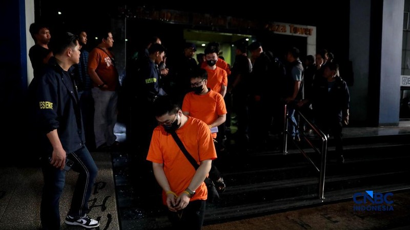 ‎Sejumlah tersangka judi online (judol) dikawal ketat oleh aparat Kepolisian keluar dari Hayam Wuruk Tower, Jakarta, Minggu (10/05/2026). Tim gabungan Bareskrim Polri dan Polda Metro Jaya mengamankan 321 orang yang terdiri 321 WNA yang diamankan, terdiri dari 57 WN Tiongkok atau China, 228 WN Vietnam, 11 WN Laos, 13 WN Myanmar, 3 WN Malaysia, 5 WN Thailand, 3 WN Kamboja. Para pelaku ditangkap tangan saat melakukan judi online. Mereka dipindahkan secara bertahan untuk menjalani pemeriksaan lebih lanjut di Kantor Imigrasi Jakarta. (CNBC Indonesia/Muhammad Sabki)