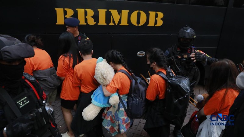 ‎Sejumlah tersangka judi online (judol) dikawal ketat oleh aparat Kepolisian keluar dari Hayam Wuruk Tower, Jakarta, Minggu (10/05/2026). Tim gabungan Bareskrim Polri dan Polda Metro Jaya mengamankan 321 orang yang terdiri 321 WNA yang diamankan, terdiri dari 57 WN Tiongkok atau China, 228 WN Vietnam, 11 WN Laos, 13 WN Myanmar, 3 WN Malaysia, 5 WN Thailand, 3 WN Kamboja. Para pelaku ditangkap tangan saat melakukan judi online. Mereka dipindahkan secara bertahan untuk menjalani pemeriksaan lebih lanjut di Kantor Imigrasi Jakarta. (CNBC Indonesia/Muhammad Sabki)