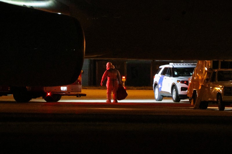 Seorang petugas dengan pakaian pelindung biohazard membantu proses penurunan penumpang yang dievakuasi dari kapal pesiar MV Hondius, yang terkena wabah hantavirus, dan tiba dengan pesawat sewaan di Bandara Eppley di Omaha, Nebraska, AS, Senin (11/5/2026). (REUTERS/Hayden Smith)