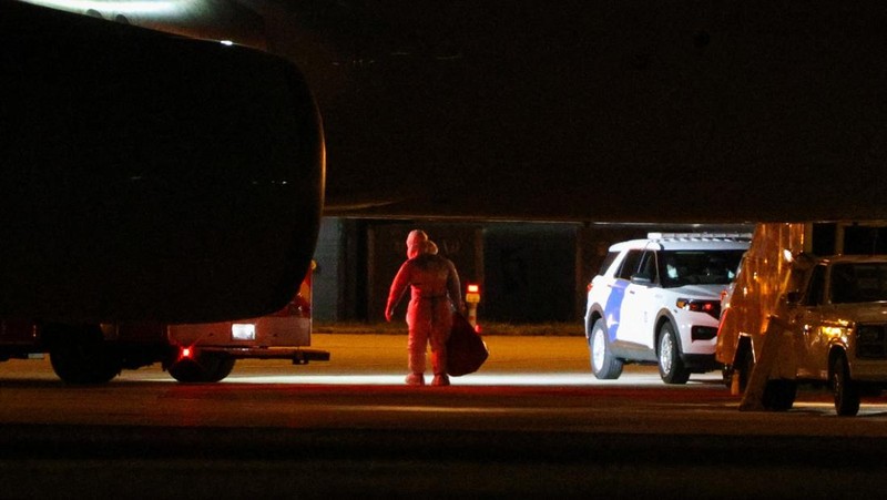Seorang petugas dengan pakaian pelindung biohazard membantu proses penurunan penumpang yang dievakuasi dari kapal pesiar MV Hondius, yang terkena wabah hantavirus, dan tiba dengan pesawat sewaan di Bandara Eppley di Omaha, Nebraska, AS, Senin (11/5/2