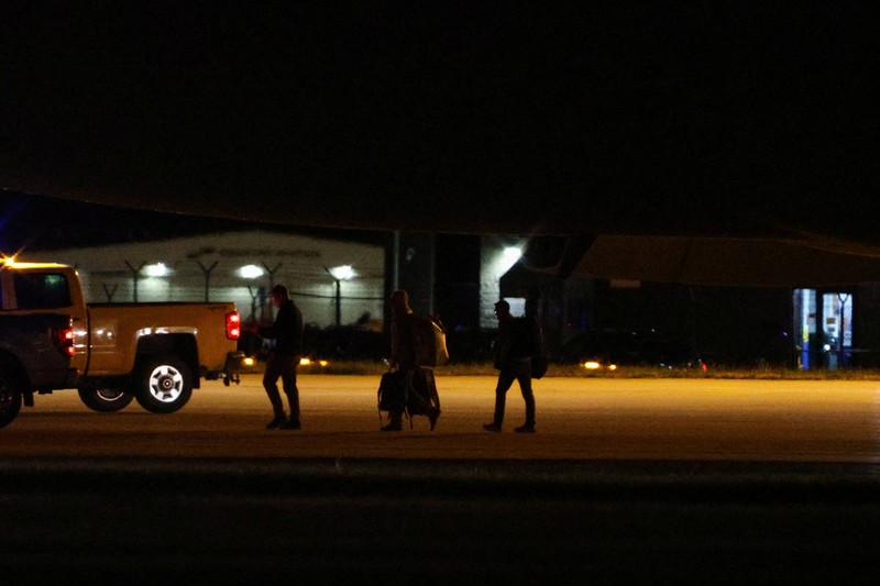 Seorang petugas dengan pakaian pelindung biohazard membantu proses penurunan penumpang yang dievakuasi dari kapal pesiar MV Hondius, yang terkena wabah hantavirus, dan tiba dengan pesawat sewaan di Bandara Eppley di Omaha, Nebraska, AS, Senin (11/5/2026). (REUTERS/Hayden Smith)