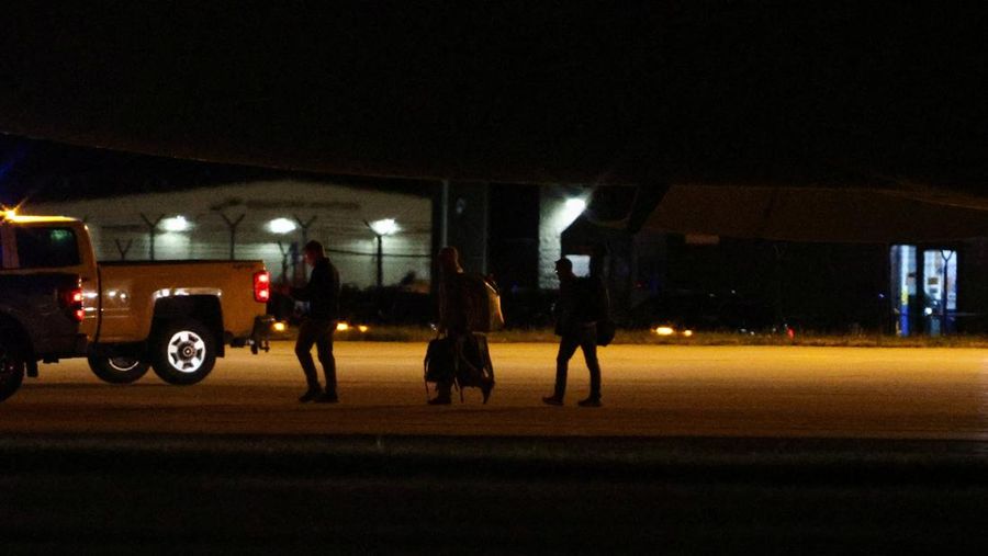 Seorang petugas dengan pakaian pelindung biohazard membantu proses penurunan penumpang yang dievakuasi dari kapal pesiar MV Hondius, yang terkena wabah hantavirus, dan tiba dengan pesawat sewaan di Bandara Eppley di Omaha, Nebraska, AS, Senin (11/5/2