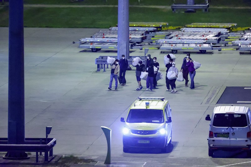 Personel berseragam hazmat berjalan di dekat pesawat yang membawa penumpang yang dievakuasi dari kapal pesiar MV Hondius, yang terkena wabah hantavirus, setelah mendarat di Pangkalan Udara Eindhoven di Eindhoven, Belanda, 12 Mei 2026. (REUTERS/Piroschka van de Wouw)
