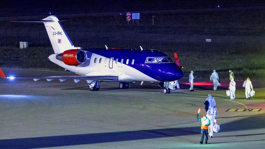 Personel berseragam hazmat berjalan di dekat pesawat yang membawa penumpang yang dievakuasi dari kapal pesiar MV Hondius, yang terkena wabah hantavirus, setelah mendarat di Pangkalan Udara Eindhoven di Eindhoven, Belanda, 12 Mei 2026. (REUTERS/Pirosc